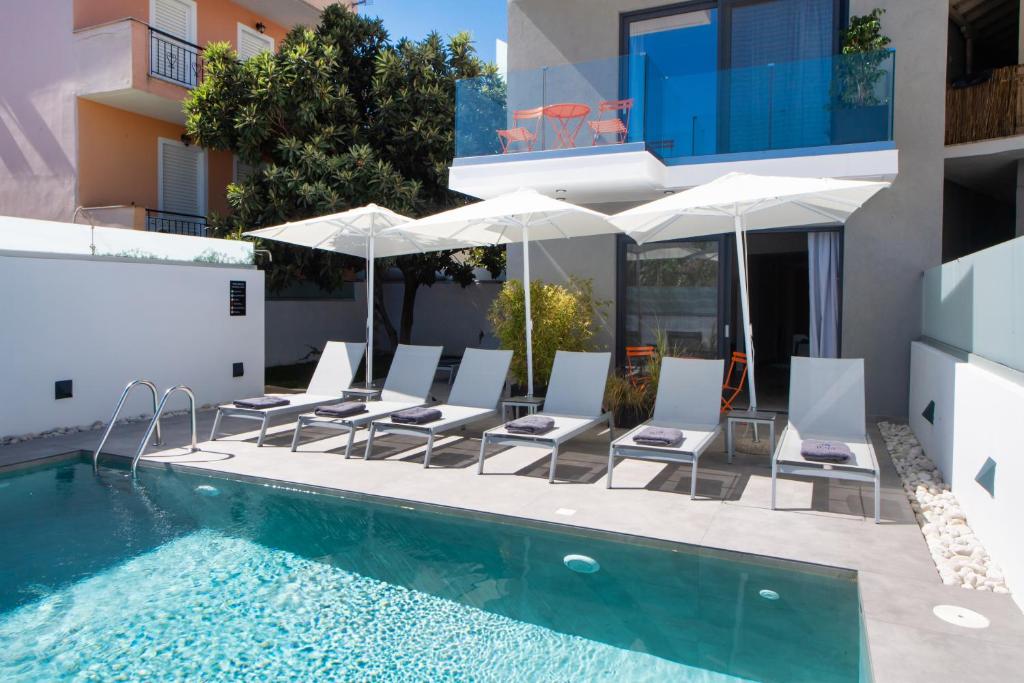 uma piscina com cadeiras e guarda-sóis ao lado de um edifício em Azul Apartments em Nydri
