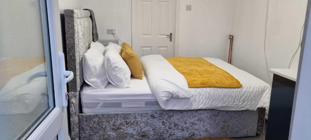 een slaapkamer met een bed met witte en gele kussens bij 1 bed studio in Luton