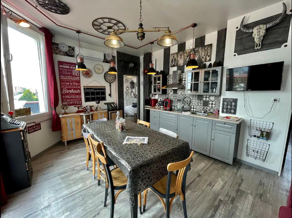 eine Küche mit einem Tisch und Stühlen in der Unterkunft Maison de l'Horloge in Riorges