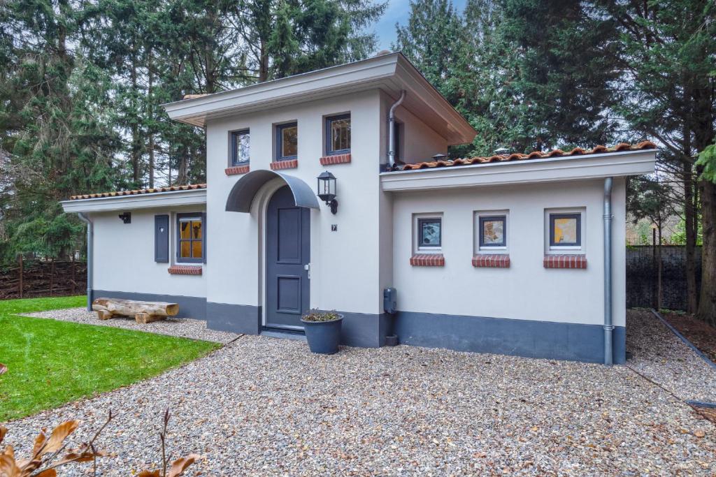 una pequeña casa blanca con una puerta azul en Boshof 7, en Ermelo