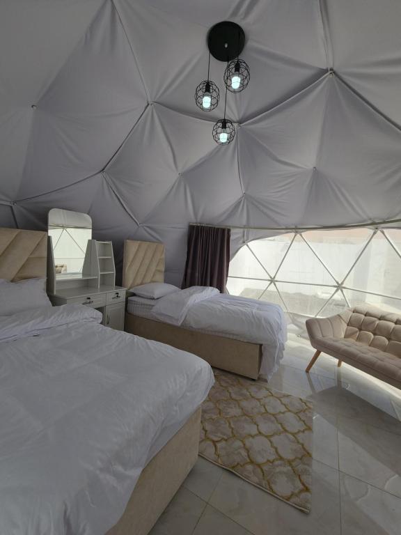 a bedroom with two beds and a tent at Blue Dome Chalet شاليه القبة الزرقاء in Al Raka