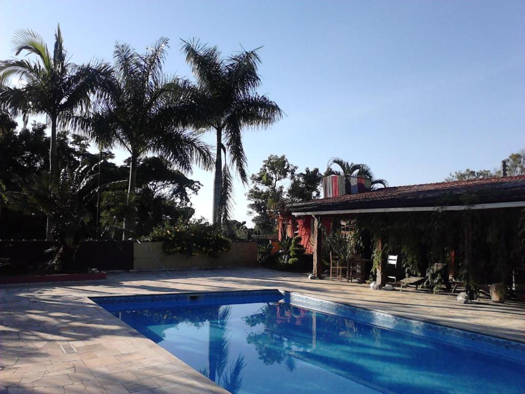 a swimming pool in front of a house with palm trees at Pousada Atelier Aly da Costa in Iguape