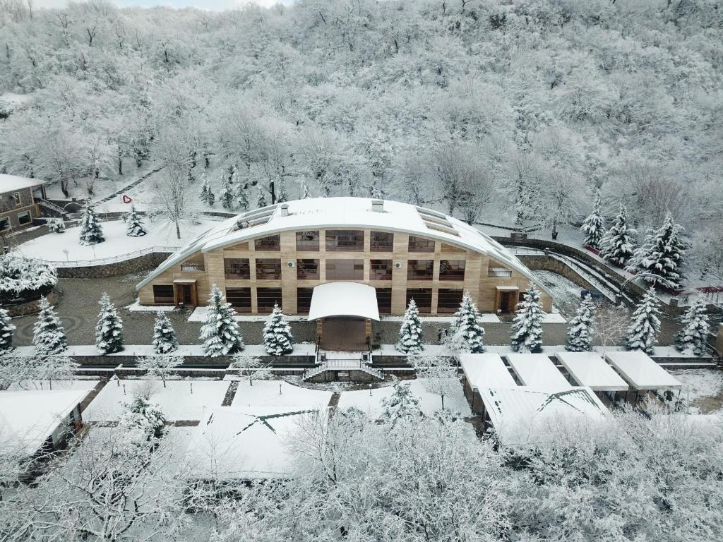 a building covered in snow with trees in front of it at Ladera Resort Qusar in Qusar