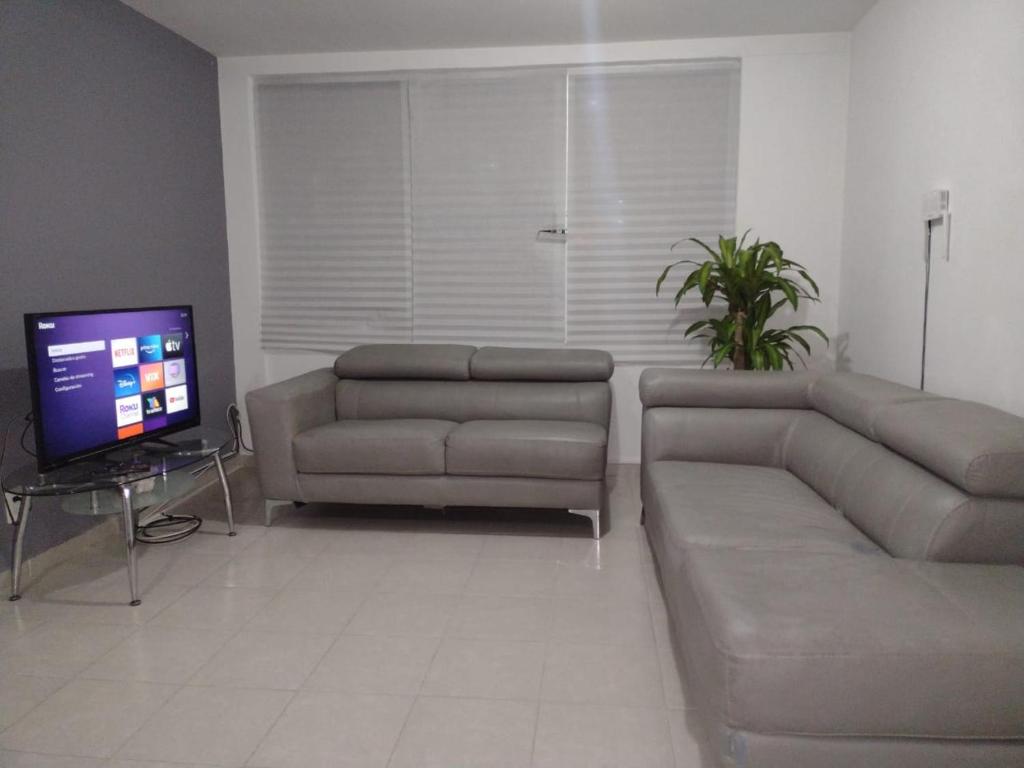 een woonkamer met een bank en een televisie bij Piso entero, cómodo y moderno in Mexico-Stad