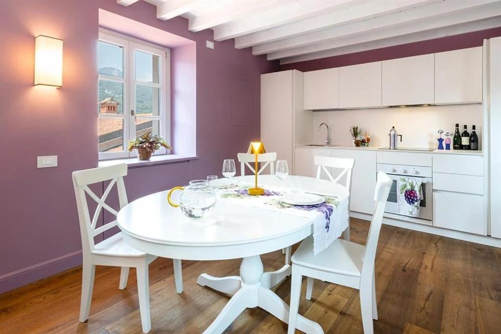 een witte tafel en stoelen in een keuken met paarse muren bij Isola Bella Apartments - Via Villa 28 in Stresa