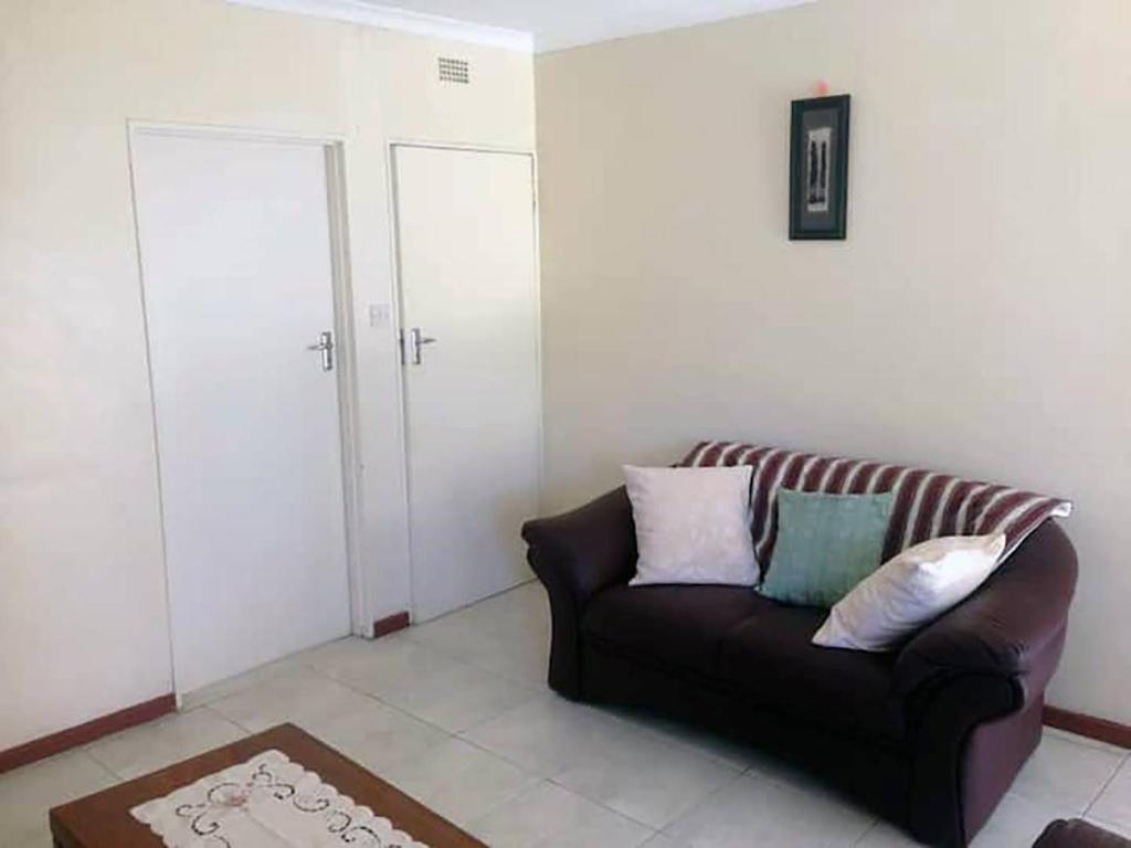 sala de estar con sofá y almohadas en 2 bed guesthouse in Mabelreign - 2012 en Harare
