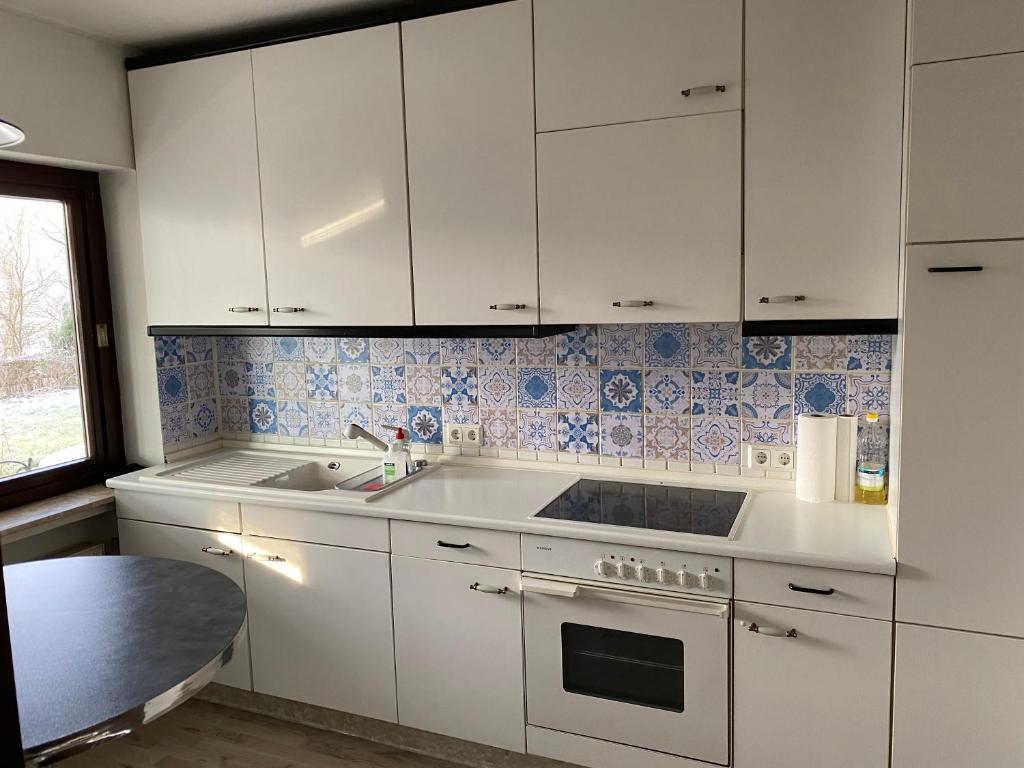 a kitchen with white cabinets and a sink at Schöne Ferienwohnung mit Waldblick in Dillenburg in Dillenburg