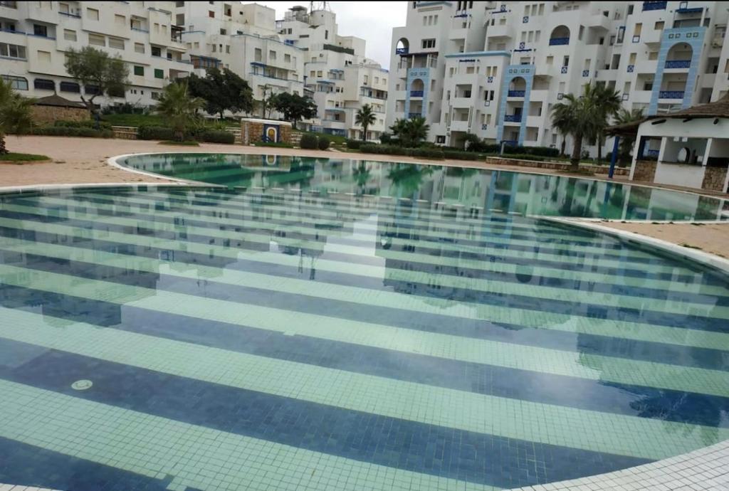 ein großer Pool vor einigen Apartmentgebäuden in der Unterkunft Cité Jardin - Appartement Martil avec Climatisation in Martil