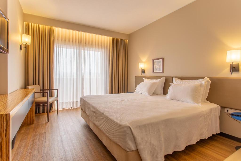 a hotel room with a large bed with white pillows at Nova Cruz Hotel in Santa Maria Da Feira