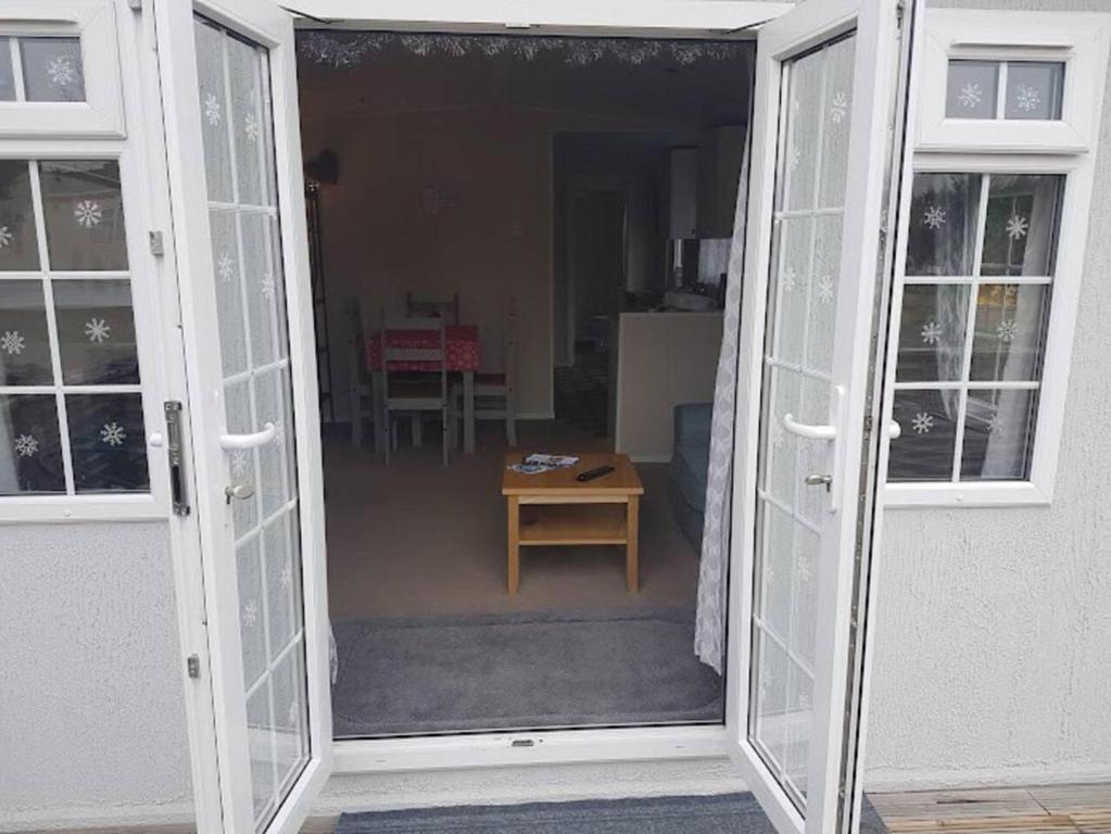 una puerta abierta a una sala de estar con mesa en Lovely 2-Bed Chalet at Robinhood Retreat Free park, en Nottingham