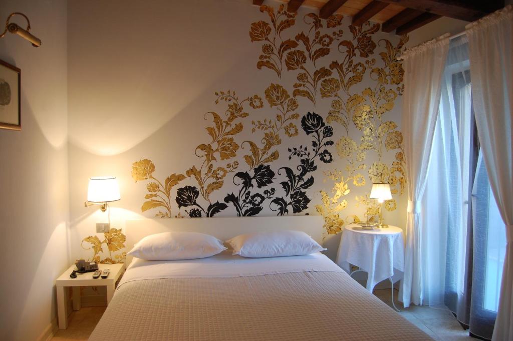 a bedroom with a white bed with a floral wallpaper at La Corte in Tolentino