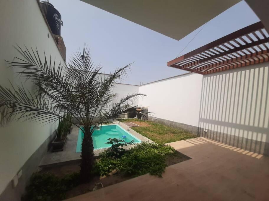 uma piscina com uma palmeira ao lado de um edifício em Hermosa Casa de Playa km 90.5 em Bujama Baja