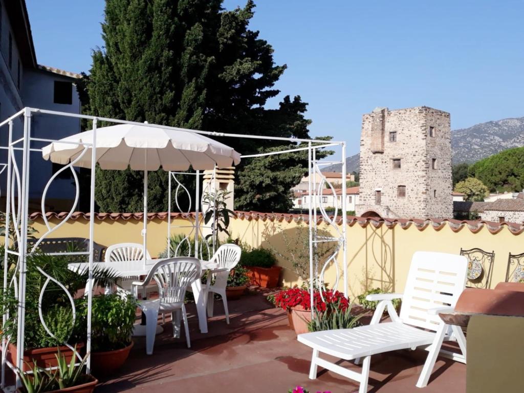 a patio with white chairs and an umbrella and a castle at Casa Lupino in Orosei