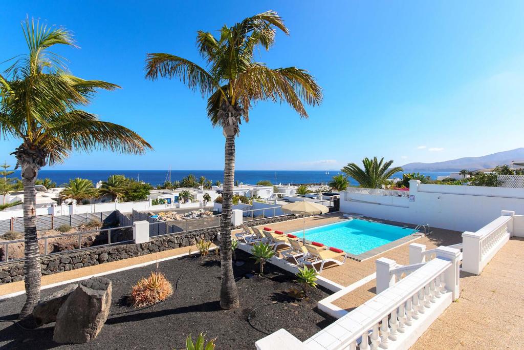 a resort with a swimming pool and palm trees at La Casa Del Puerto, Puerto Calero in Puerto Calero