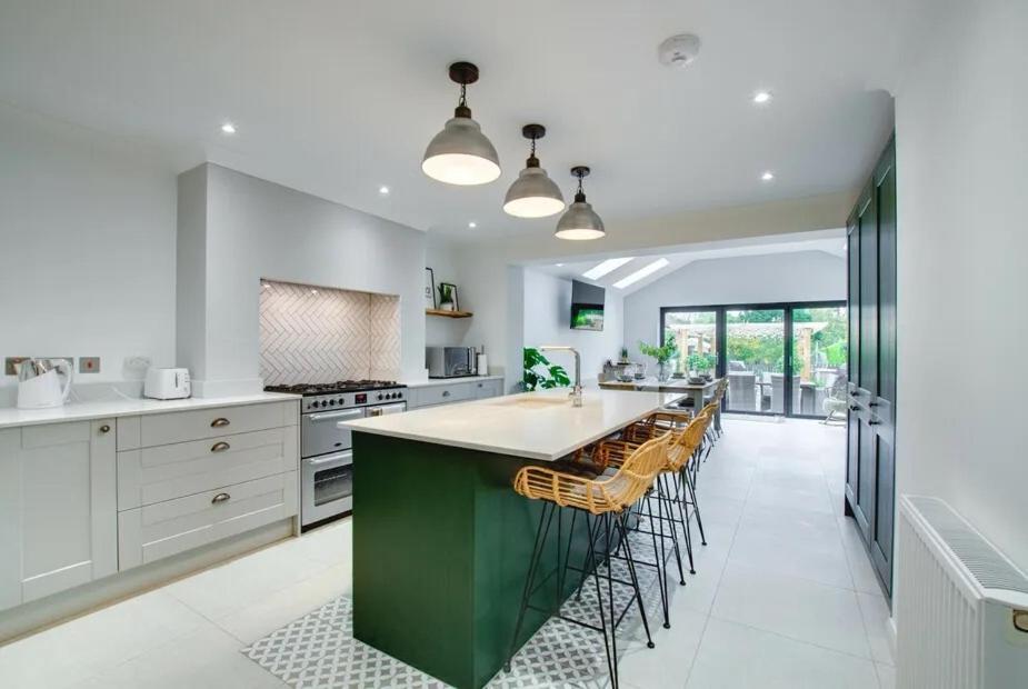 a kitchen with a large green island with chairs at Belle Vue Cottage in Downham Market