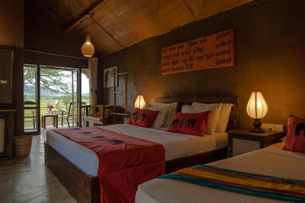 a bedroom with two beds with red and white pillows at Gaga Bees Yala in Tissamaharama