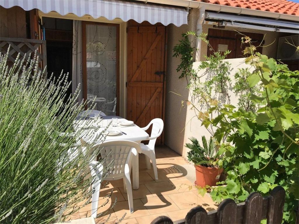 une table et des chaises sur une terrasse avec des plantes dans l'établissement Charmant pavillon à Port Leucate, 4 pers., plage et commerces à proximité, parking privé - FR-1-81-138, à Port-Leucate