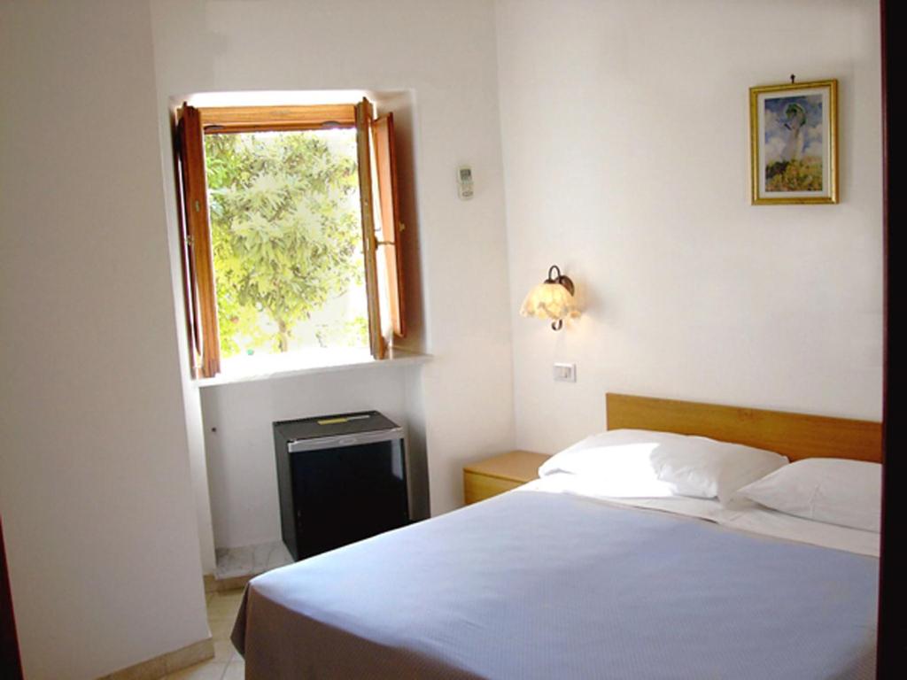 a bedroom with a white bed and a window at Ludovica Apartment in Positano