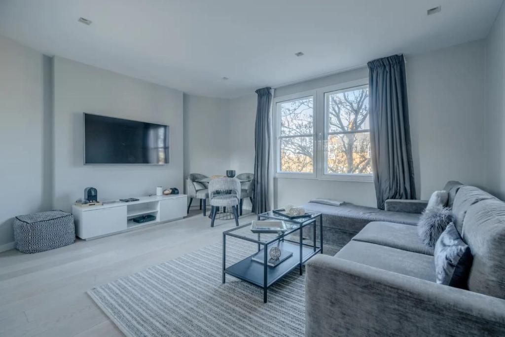 a living room with a couch and a table at Modern and Luxurious 2 Bedroom Flat - Barons Court in London