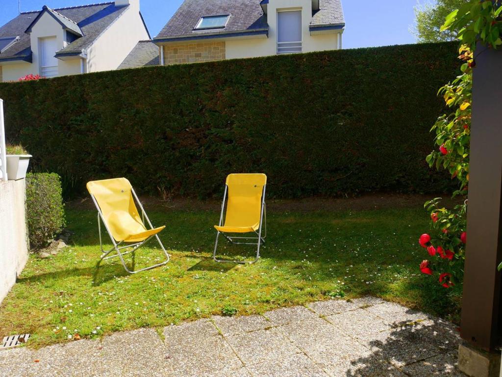 deux chaises jaunes assises dans l'herbe près d'une haie dans l'établissement Appartement à Carnac: 3 pièces, 6 pers, 45m², Wifi, proche plages, terrasse, garage - FR-1-477-70, à Carnac