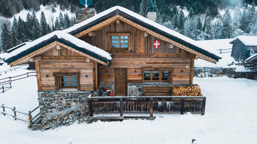 domek z bali i śniegiem na dachu w obiekcie Chalet Le R'Posiao w mieście Morzine