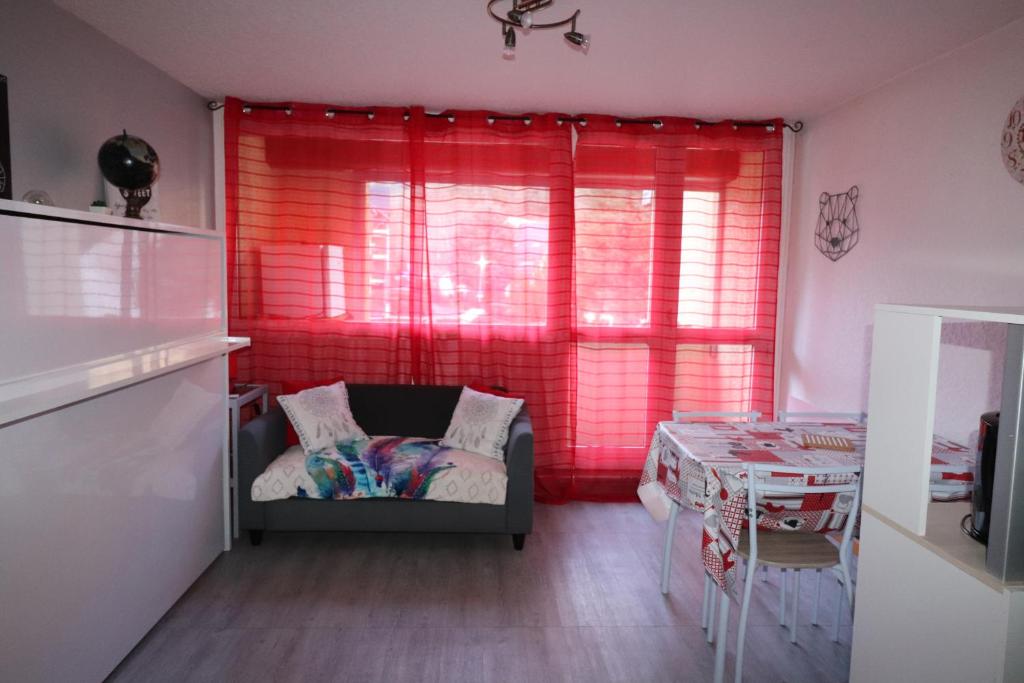 een woonkamer met een bank en een rood raam bij Studio St Lary village-vue montagne. in Saint-Lary-Soulan