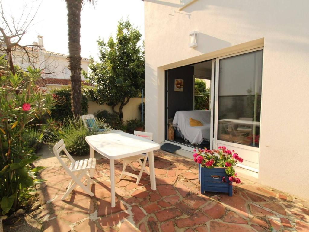 une table et des chaises blanches sur une terrasse en briques dans l'établissement Appartement rénové à Royan, proche plage, terrasse, parking privé - FR-1-494-102, à Royan