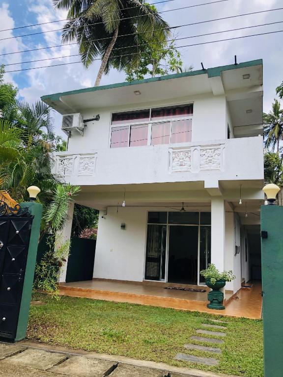 a white house with a palm tree in front of it at Nilan Villa in Koggala