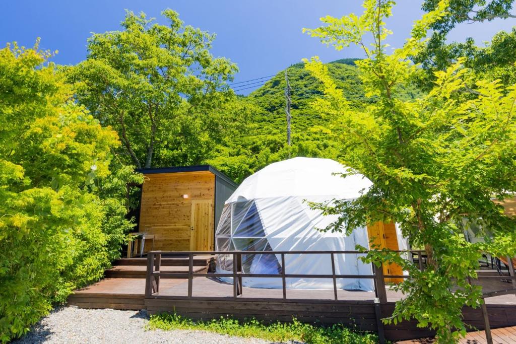 invernadero en un jardín con banco y árboles en The Village Yufuin Onsen Glamping - Vacation STAY 18004v en Yufu