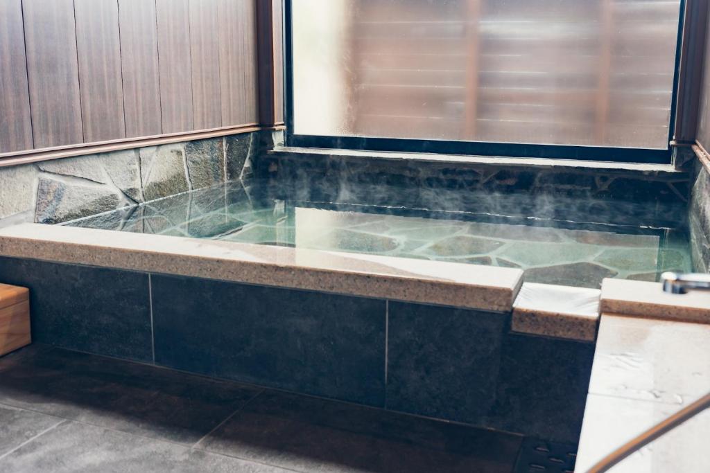a bathroom with a bath tub with a window at The Village Yufuin Onsen Glamping - Vacation STAY 17996v in Yufu