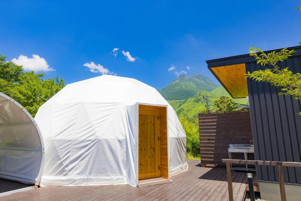 a white yurt with a wooden door on a deck at The Village Yufuin Onsen Glamping - Vacation STAY 17998v in Yufuin