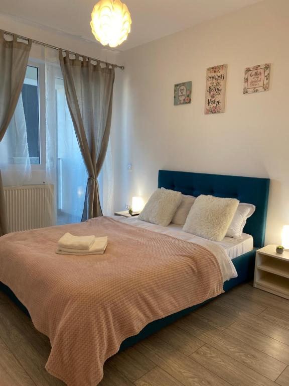 een slaapkamer met een groot bed met een blauw hoofdeinde bij Q Apartament Loft place near Palas Mall in Iaşi