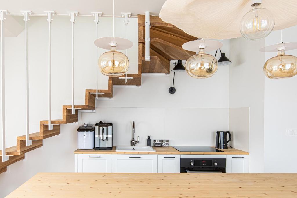 een keuken met witte kasten en een trap met verlichting bij ZAKOZNAMI- Willa WYWCZAS in Zakopane