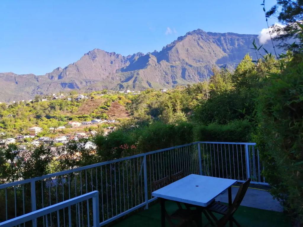 a picnic table on a balcony with mountains in the background at Les Durantas in Cilaos