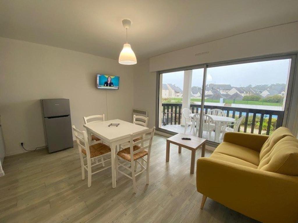un salon avec un canapé et une table avec des chaises dans l'établissement Appartement 3 pièces rénové avec piscine à Quiberon - Balcon, parking, proche plage - FR-1-478-207, à Quiberon