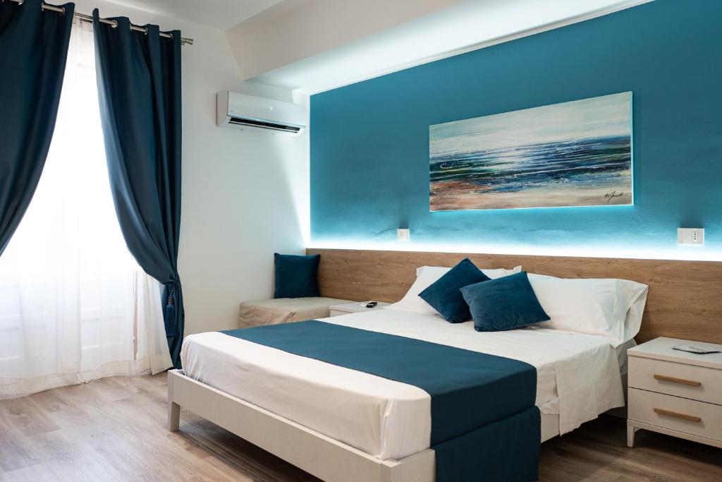 1 dormitorio con cama y pared azul en A Due Passi - Guest House, en Santo Stefano di Camastra
