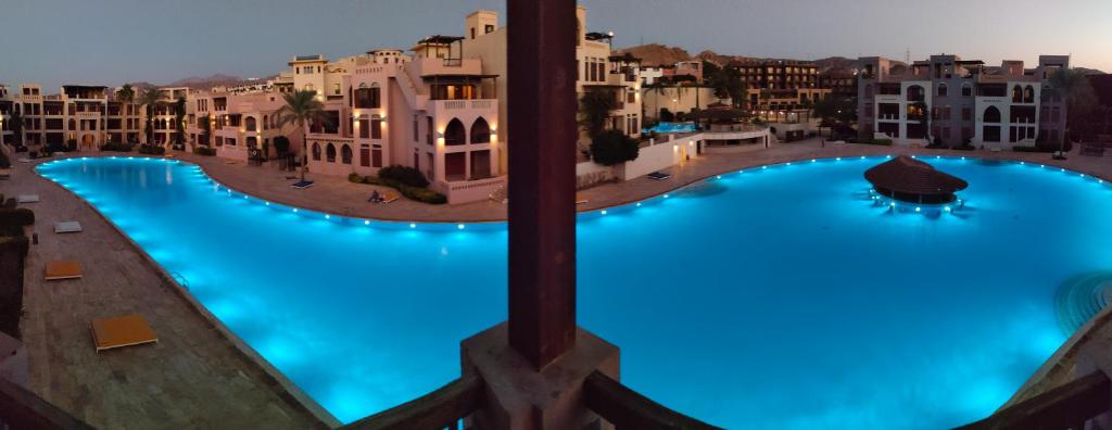 a large swimming pool with blue lighting in a city at Tala bay apartments 2 bedroom in Aqaba