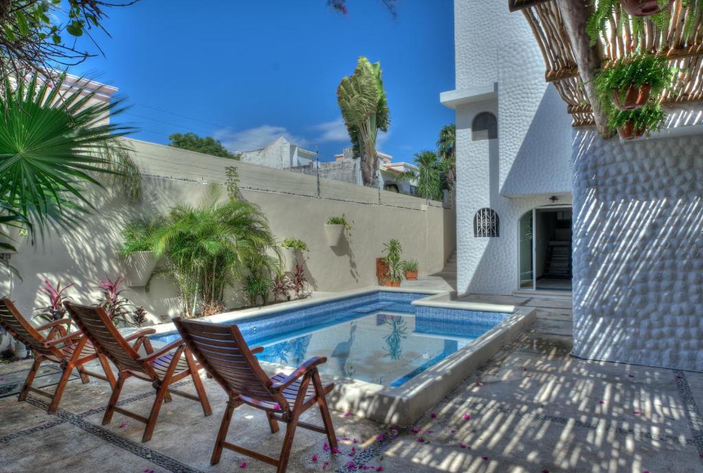 una piscina con 2 sillas y una casa en 5BR Beautiful home in downtown Cancun, 10min beach, en Cancún