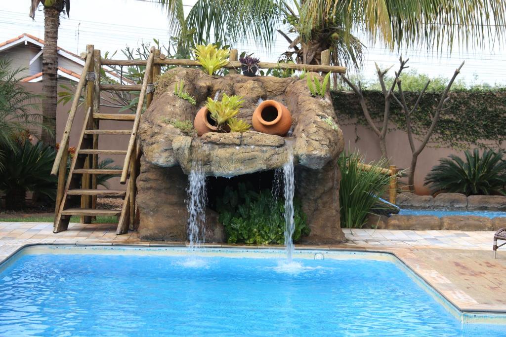 una piscina con cascada en un patio en Pousada Tia Nena, en Olímpia