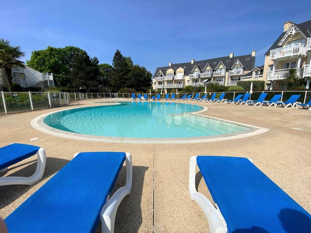- une piscine avec des chaises bleues dans un complexe dans l'établissement Appartement à Fouesnant avec piscine chauffée, proche plage et GR34 - FR-1-481-109, à Fouesnant