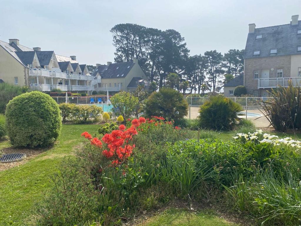 a garden with red flowers in a yard with houses at Appartement Fouesnant, 2 pièces, 4 personnes - FR-1-481-109 in Fouesnant