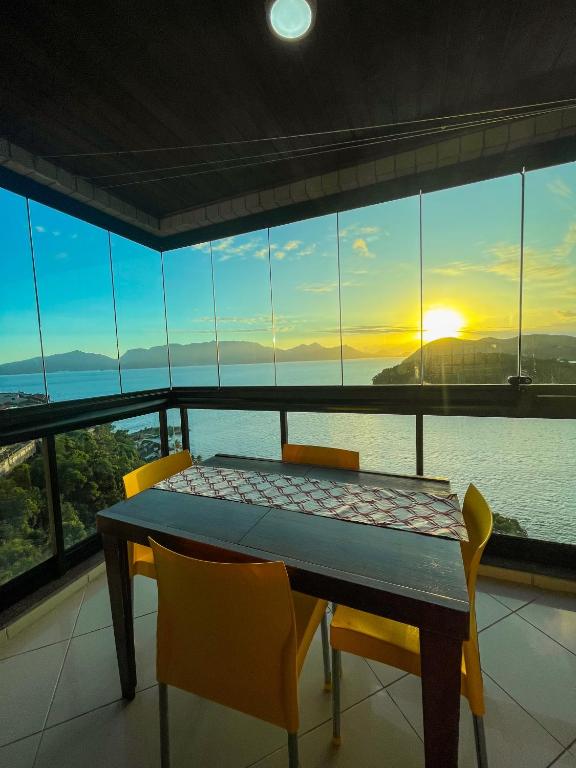 a table and chairs in a room with a view of the ocean at Apartamento Porto Real Resort (11.1 402) com vista panorâmica in Angra dos Reis