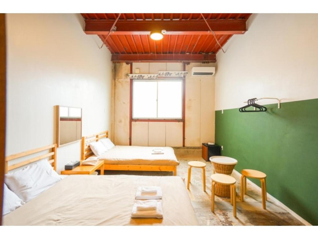 Habitación con 2 camas, 2 mesas y sillas en fan! -ABURATSU- Sports Bar & HOSTEL - Vacation STAY 78433v, en Nichinan