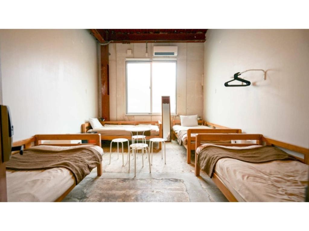 una camera con quattro letti e un tavolo con sedie di fan! -ABURATSU- Sports Bar & HOSTEL - Vacation STAY 78445v a Nichinan