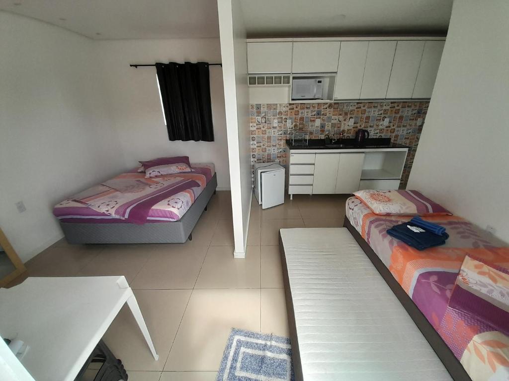 a small room with two beds and a kitchen at JK SUÍTES GARAGEM central in Pelotas