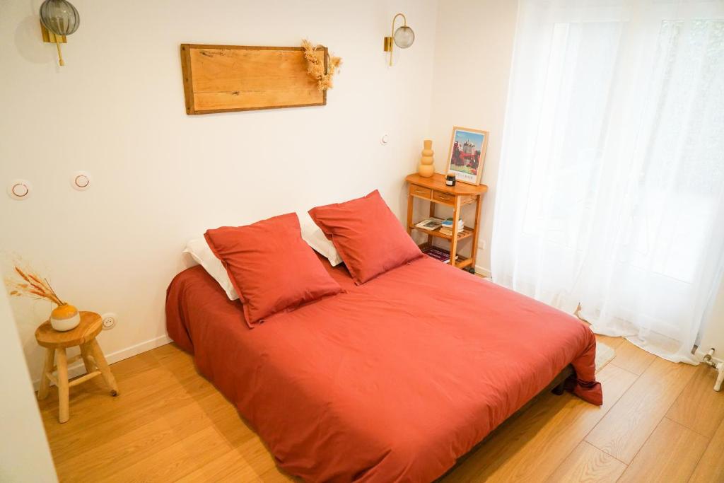 a bedroom with a bed with red sheets and a window at Le doux refuge - SPA privatif - Romantique - Calme in Châteauroux