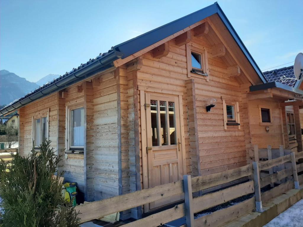 una cabaña de madera con una valla delante en Fuxhouse mit Carport -Faakersee -Aichwaldsee gratis Seezugang, en Ledenitzen