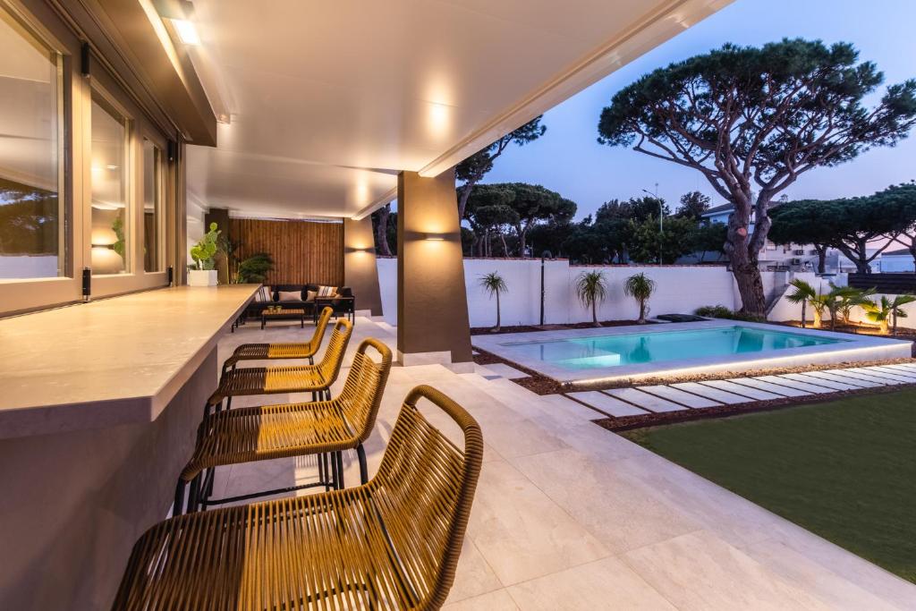 een patio met stoelen en een zwembad bij Impresionante villa en Playa de la Barrosa in Chiclana de la Frontera