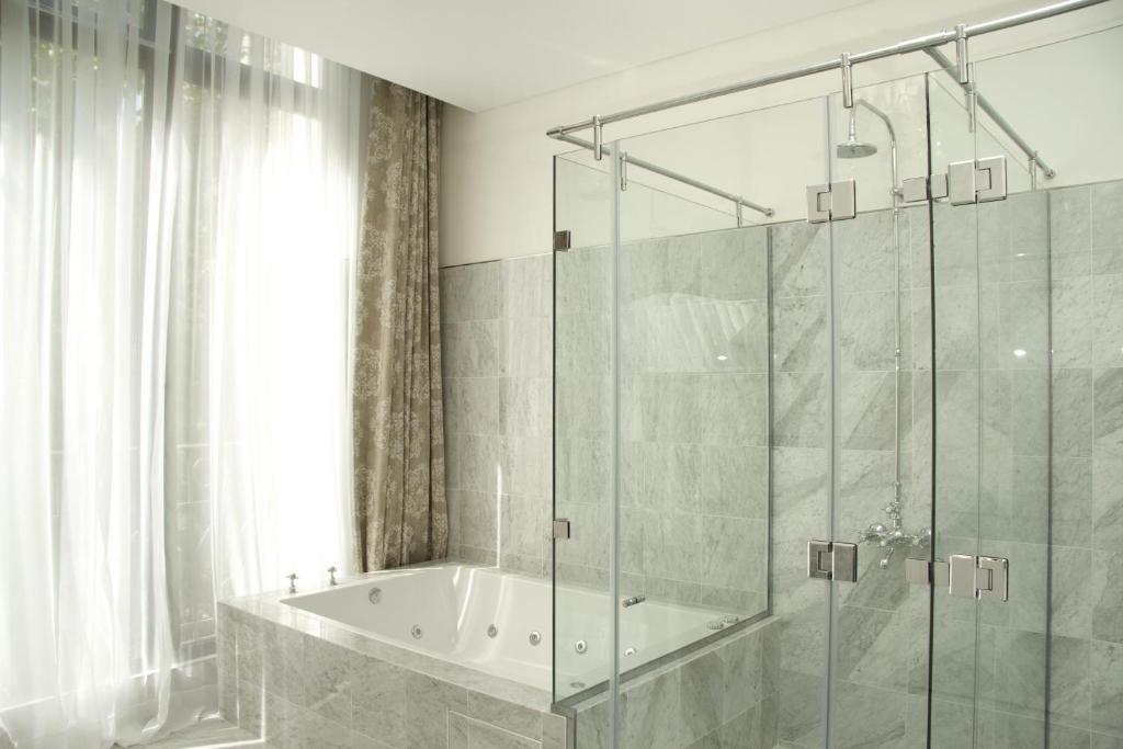 a bathroom with a tub and a glass shower at Tango de Mayo Hotel in Buenos Aires