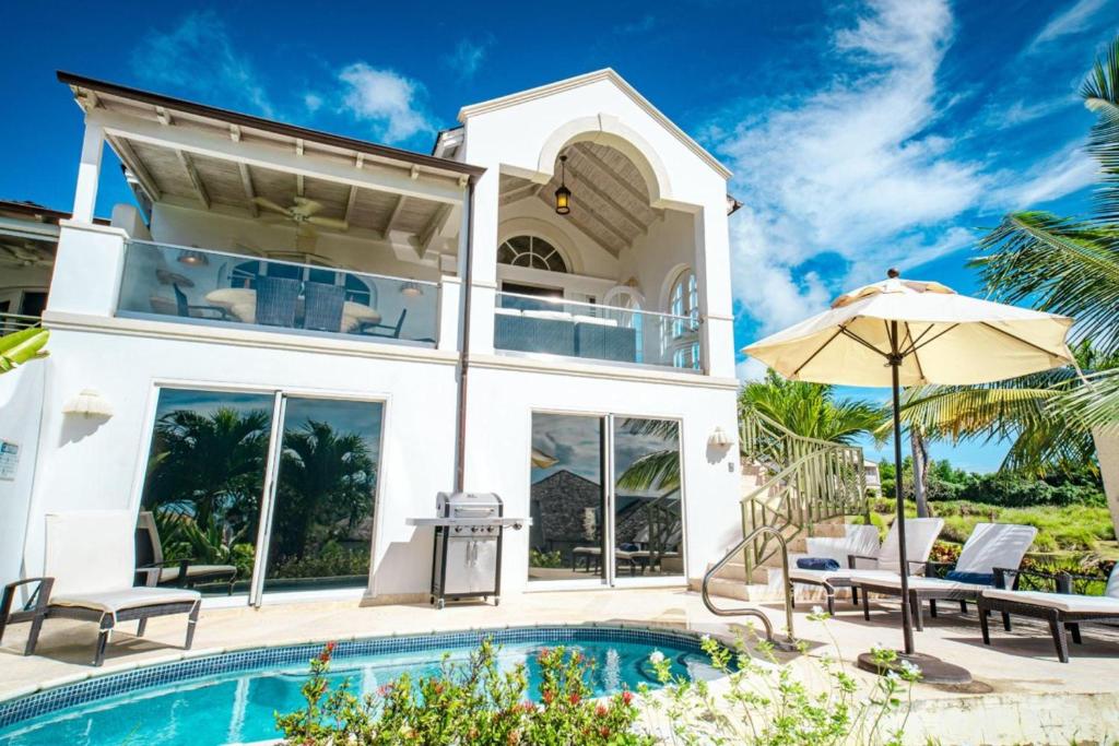 a villa with a swimming pool and a house at Royal Westmoreland - Sugar Cane Ridge by Blue Sky Luxury in Saint James